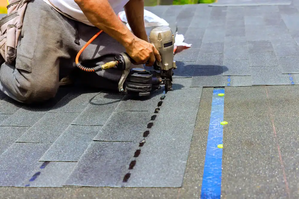 Experienced roofing contractor from Bay Area Exteriors in Talbot County, Maryland, carefully securing shingles with a nail gun, demonstrating expert roofing techniques