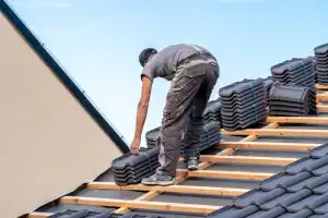 A roofer installing high-quality roof tiles on a home in Talbot County, MD, showcasing precise craftsmanship for Bay Area Exteriors’ roofing services