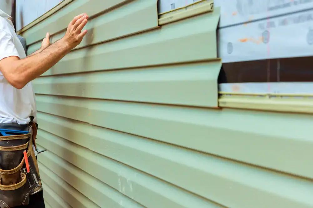 Skilled worker installing green siding on a home in Talbot County, MD, enhancing the property's curb appeal with high-quality materials from Bay Area Exteriors